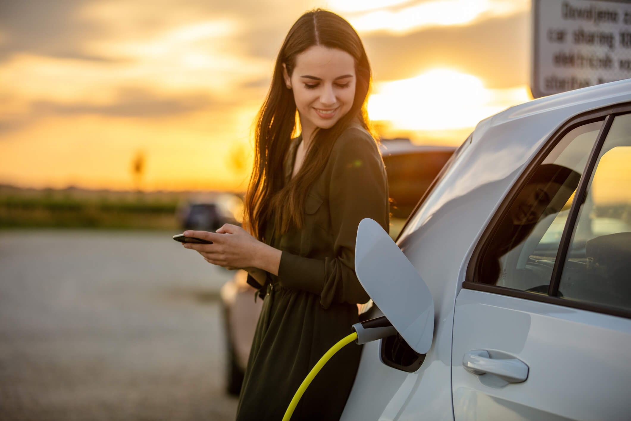 Smiling woman leaning on a charging car