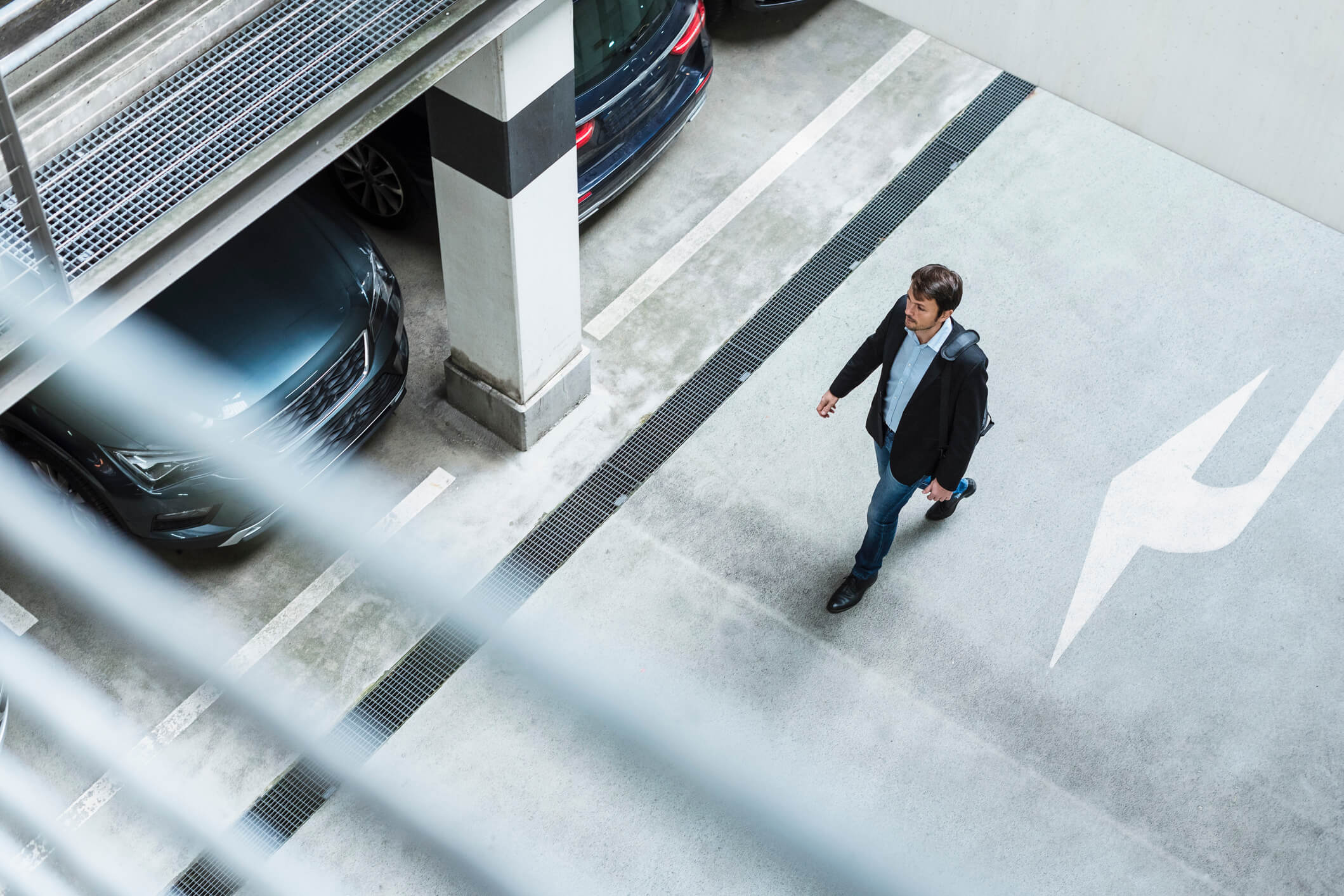 A man walking in the underground car park between the cars