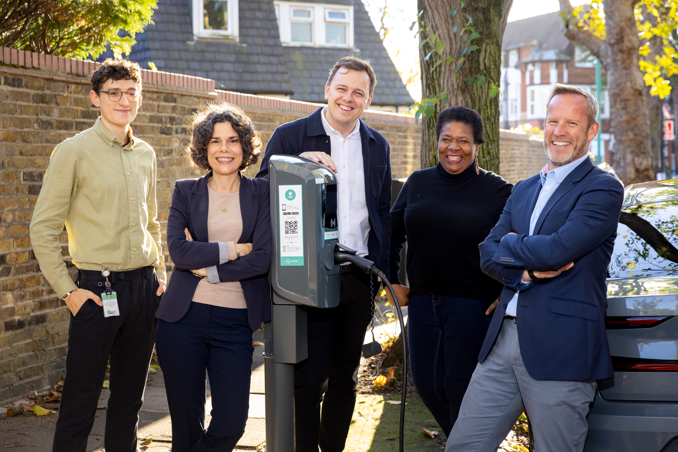 smiling people standing around charging point