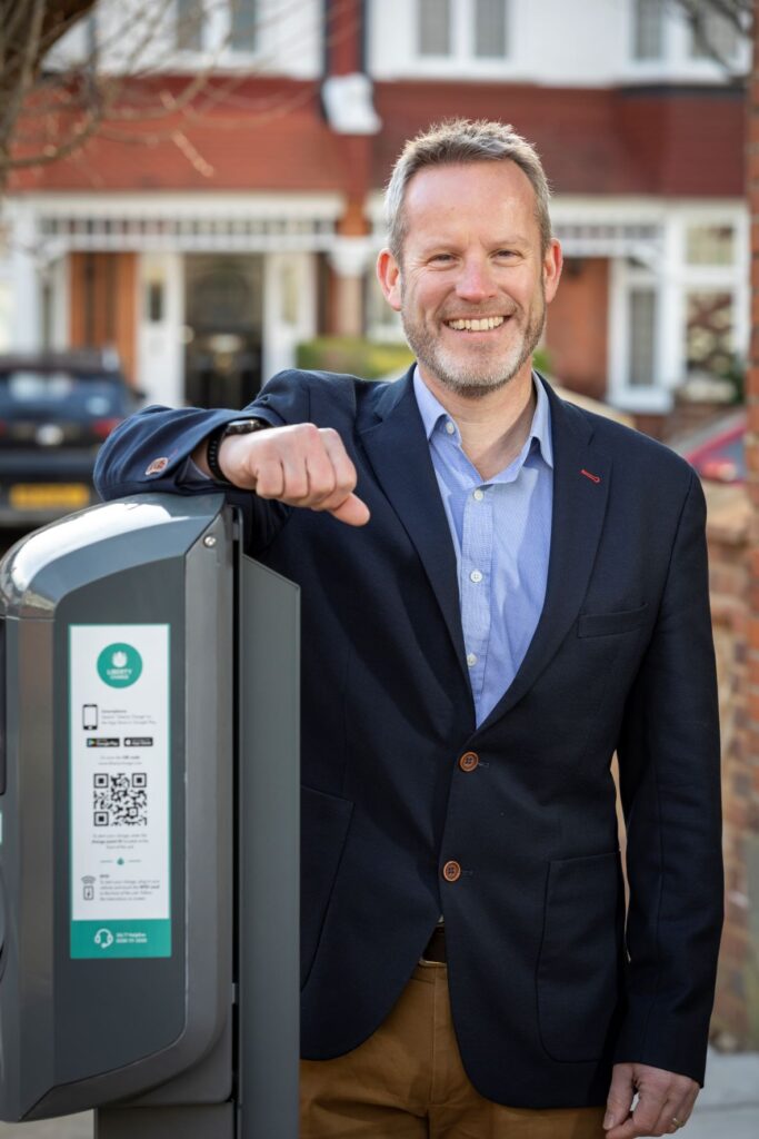 Smiling man leaning on a charging point