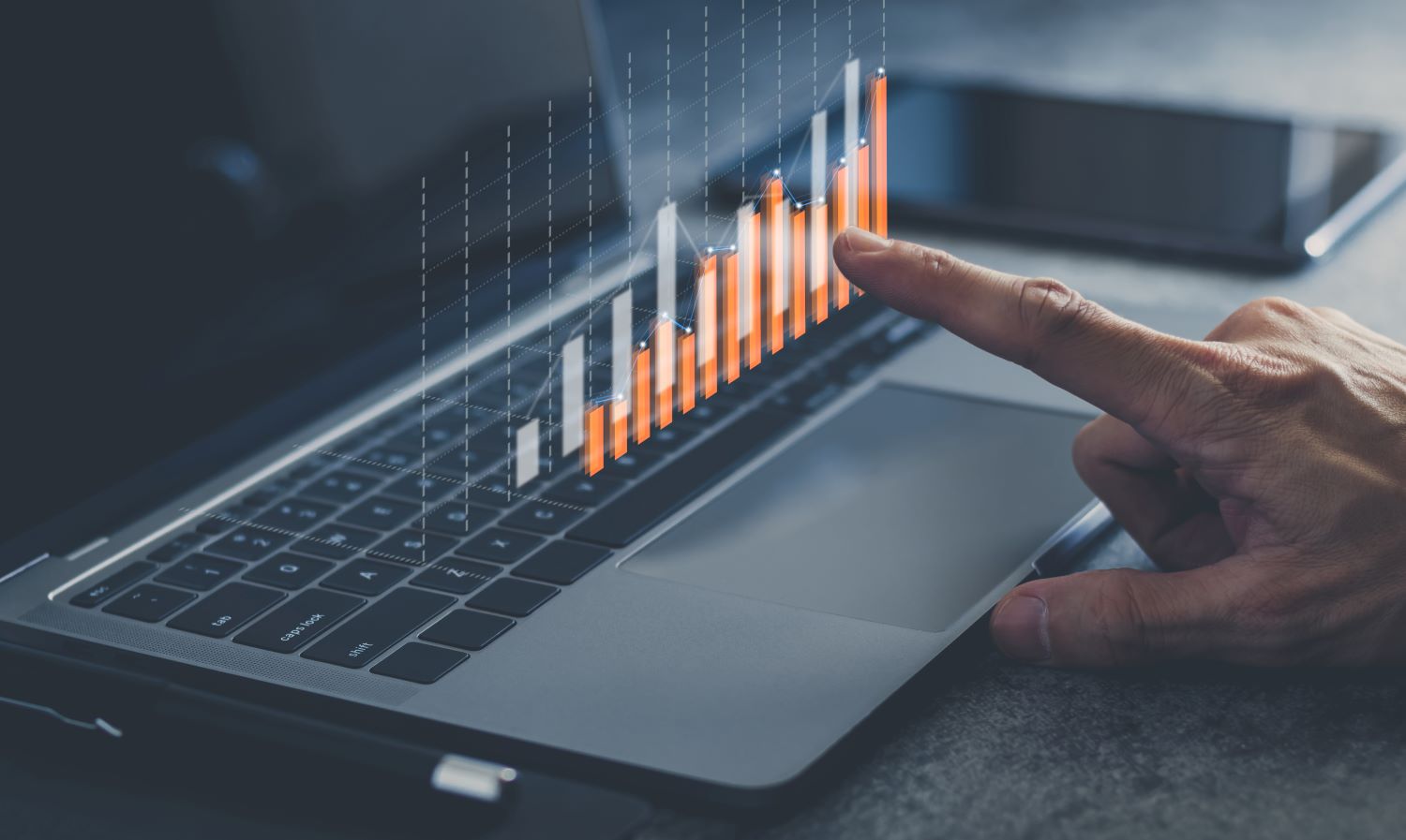 A hand pointing at a data graph that desplays over a laptop