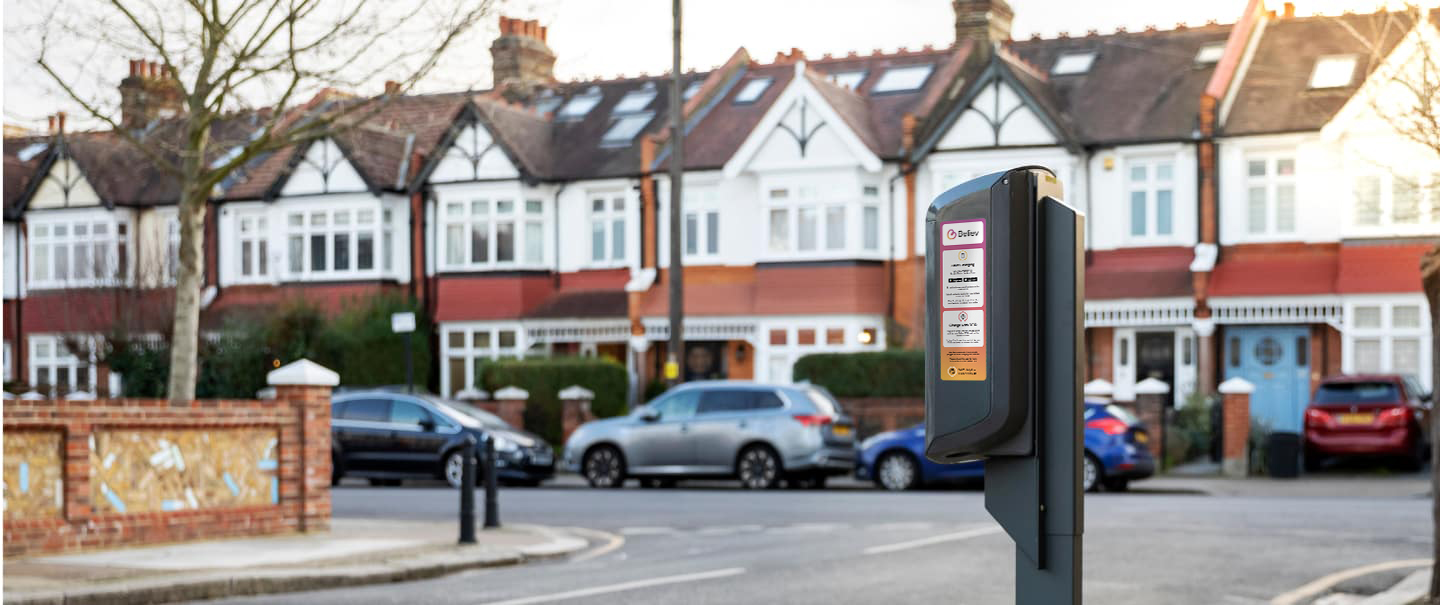 Road, car charger, residential buildings in the background